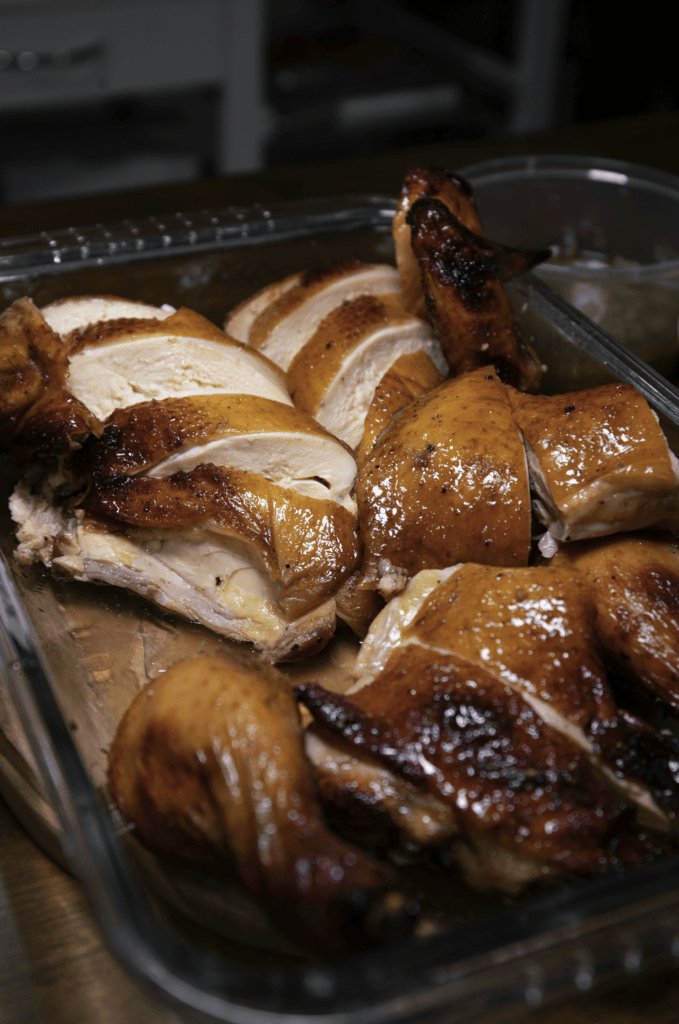 A golden-brown rotisserie chicken with a side of fresh herbs, showcasing a perfectly cooked meal for various recipes.