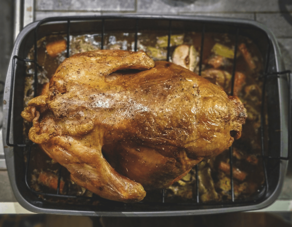 A golden-brown rotisserie chicken with a side of fresh herbs, showcasing a perfectly cooked meal for various recipes.