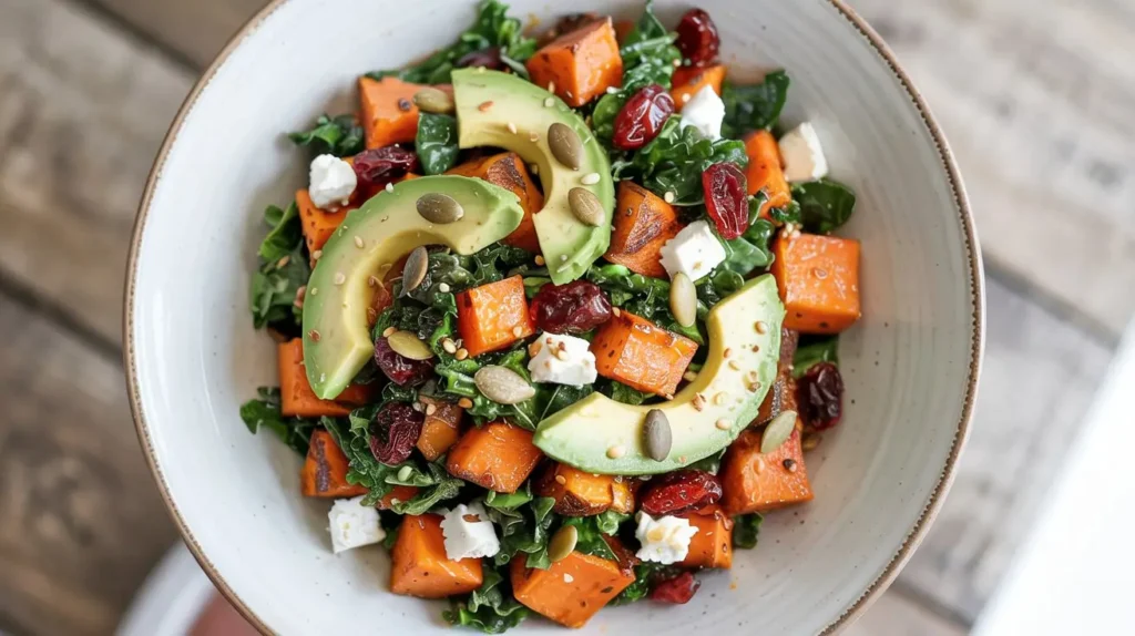 Top view of Sweet Potato Kale Salad with avocado, cranberries, and feta in a white bowl